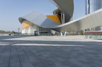 a building with a curved wall is in front of some buildings with skyscrapers behind it