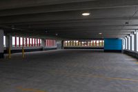 an empty parking garage with light posts in the distance and large windows in the background