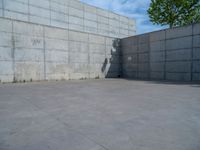 the empty parking lot in front of a wall with apartment buildings on it and a skateboarder on a ramp