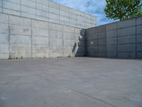 the empty parking lot in front of a wall with apartment buildings on it and a skateboarder on a ramp