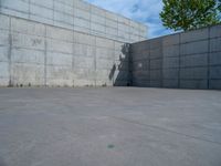 the empty parking lot in front of a wall with apartment buildings on it and a skateboarder on a ramp