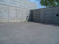 the empty parking lot in front of a wall with apartment buildings on it and a skateboarder on a ramp