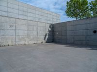 the empty parking lot in front of a wall with apartment buildings on it and a skateboarder on a ramp