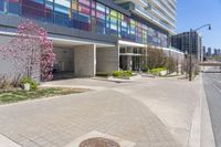 there is a large building on the street corner near the grass and flowers of trees