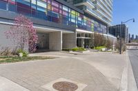 there is a large building on the street corner near the grass and flowers of trees