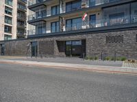 there is a building with many windows next to the road as a person rides a motorcycle on the sidewalk