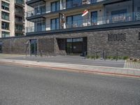 there is a building with many windows next to the road as a person rides a motorcycle on the sidewalk