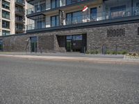 there is a building with many windows next to the road as a person rides a motorcycle on the sidewalk