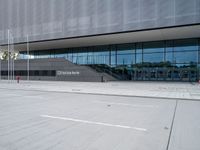 the exterior of a building with glass windows on it, with a bus parked in front