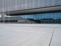 the exterior of a building with glass windows on it, with a bus parked in front