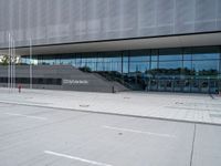 the exterior of a building with glass windows on it, with a bus parked in front