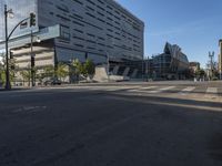 the corner of an empty street with several people on it's side and buildings around