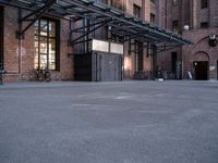 a large empty lot is surrounded by brick buildings and has some bikes parked on the pavement