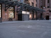 a large empty lot is surrounded by brick buildings and has some bikes parked on the pavement