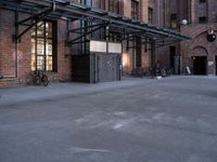 a large empty lot is surrounded by brick buildings and has some bikes parked on the pavement