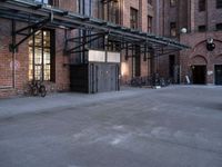 a large empty lot is surrounded by brick buildings and has some bikes parked on the pavement