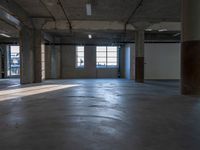 an empty building with concrete floors and a lot of windows showing the outside from inside