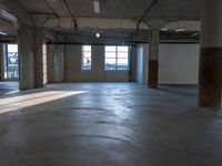 an empty building with concrete floors and a lot of windows showing the outside from inside