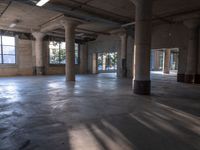 an empty concrete building filled with pillars and windows with sunlight streaming through it and columns