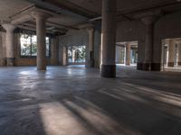 an empty concrete building filled with pillars and windows with sunlight streaming through it and columns