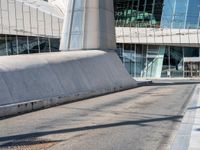 a large concrete wall on the side of a street with a man on a skateboard near by