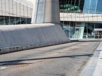 a large concrete wall on the side of a street with a man on a skateboard near by