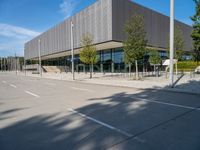 a metal building with several large trees in the foreground and some buildings near by