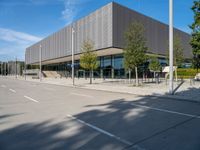 a metal building with several large trees in the foreground and some buildings near by