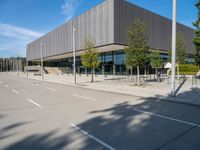 a metal building with several large trees in the foreground and some buildings near by