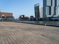 a brick walkway in front of tall buildings along a body of water in a city