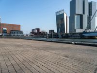 a brick walkway in front of tall buildings along a body of water in a city