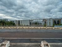 several concrete blocks and barriers on an empty road in front of large building on a cloudy day