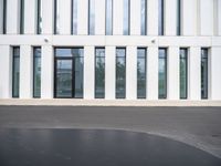 the side of an office building with windows on each floor and a large concrete oval shaped asphalt area