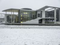 a large building sitting in the snow next to water, with people walking on the ice