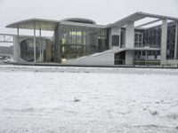 a large building sitting in the snow next to water, with people walking on the ice