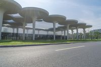 an open field next to a road that leads up into a building with multiple columns