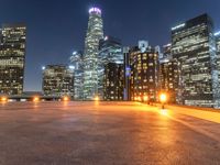 an area with a bench and firelight on top of it at night with the city lights turned on