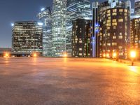 an area with a bench and firelight on top of it at night with the city lights turned on