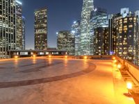 an area with a bench and firelight on top of it at night with the city lights turned on