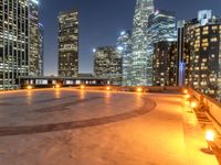 an area with a bench and firelight on top of it at night with the city lights turned on