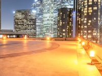 an area with a bench and firelight on top of it at night with the city lights turned on