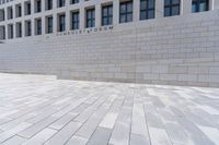 a building with an empty walkway and stone floors in front of it, outside of it is a building