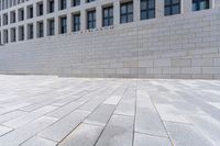 a building with an empty walkway and stone floors in front of it, outside of it is a building