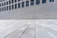 a building with an empty walkway and stone floors in front of it, outside of it is a building