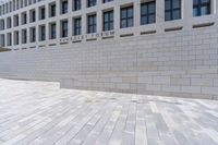 a building with an empty walkway and stone floors in front of it, outside of it is a building