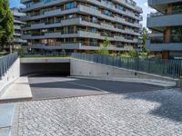 a paved walkway in front of a building with cars parked outside it on a sidewalk