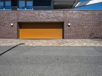 a brick building with a tan garage door next to it and the sky above it