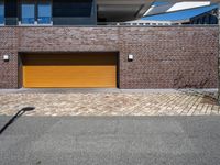 a brick building with a tan garage door next to it and the sky above it