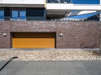 a brick building with a tan garage door next to it and the sky above it