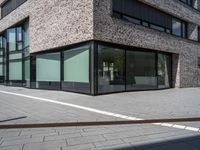 the side view of a modern office building with glass windows and a bench in front